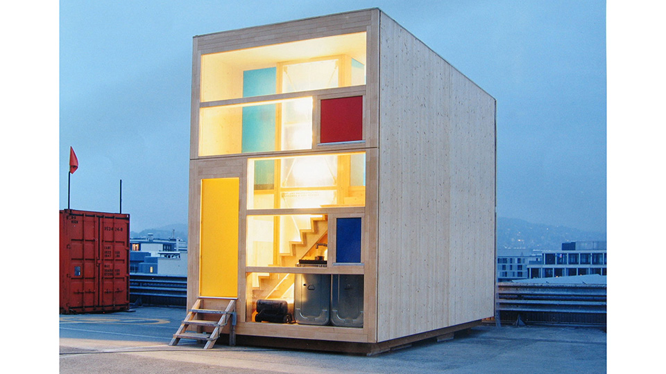 Elegantes zweistöckiges Mini-Gebäude aus Holz mit Glasfront und einzelnen bunten Elementen